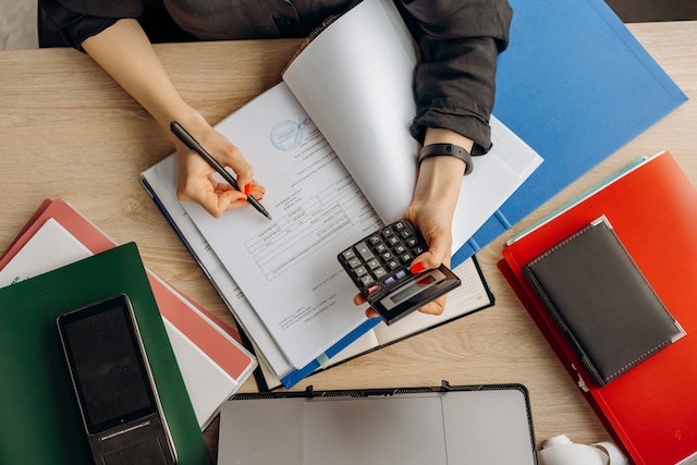 person holding a calculator and writing down numbers